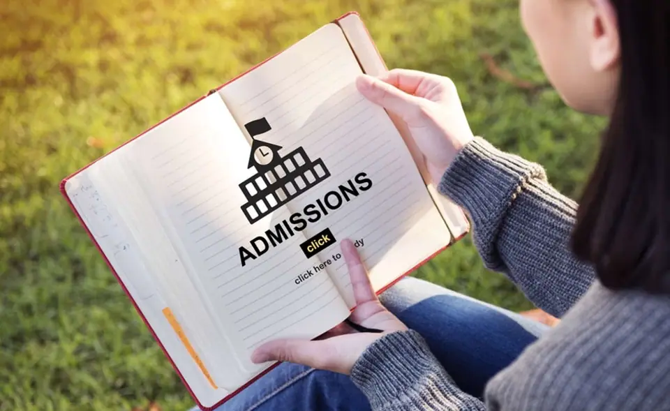 Student reading an admissions booklet outdoors