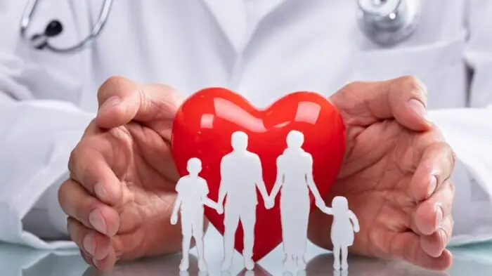 Hands protecting a paper family and heart