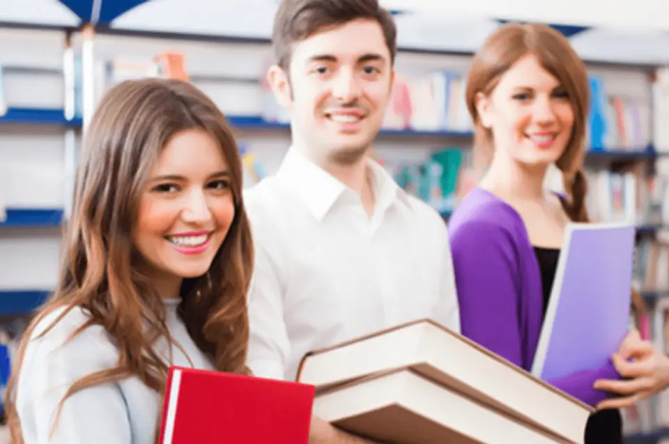 Students holding books in a university library